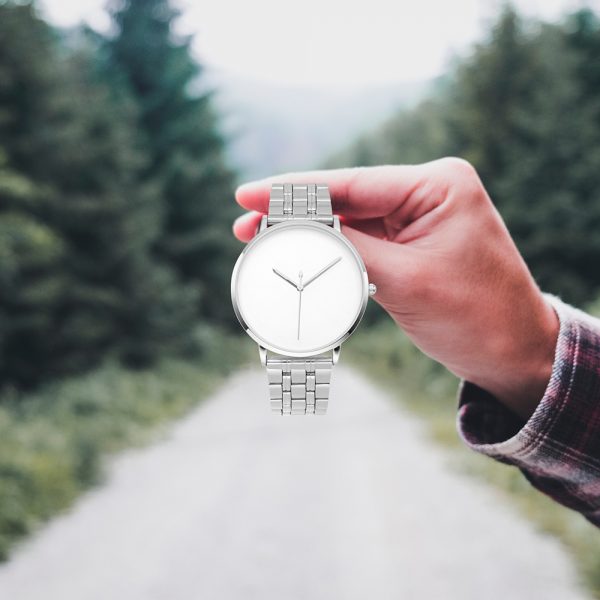 A male hand holds a silver stainless steel quartz watch