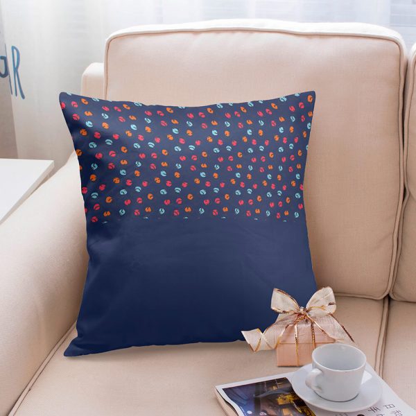 A pillow with a pattern on the top half of a dark blue is placed on the sofa