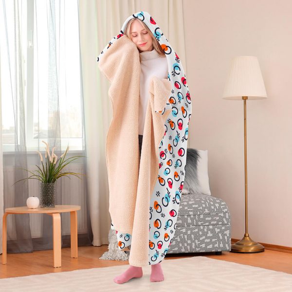 A female model wearing a patterned hooded blanket is feeling the temperature of the blanket