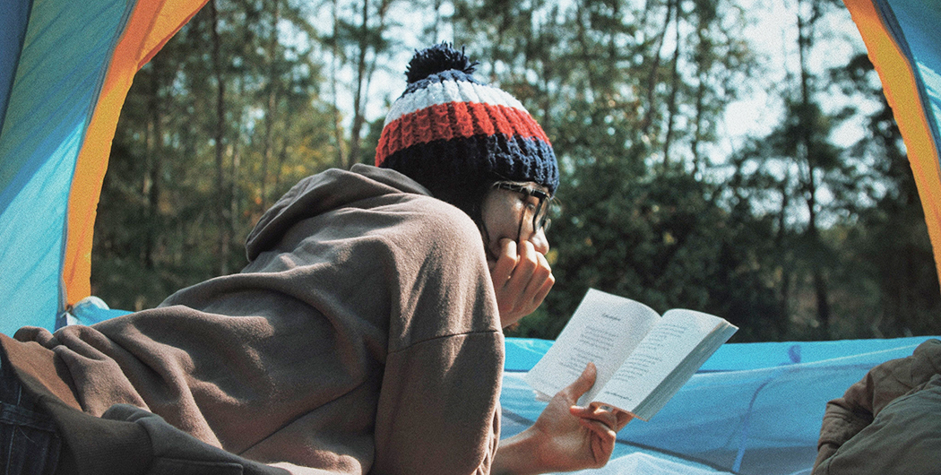 A girl is reading a book in a tent