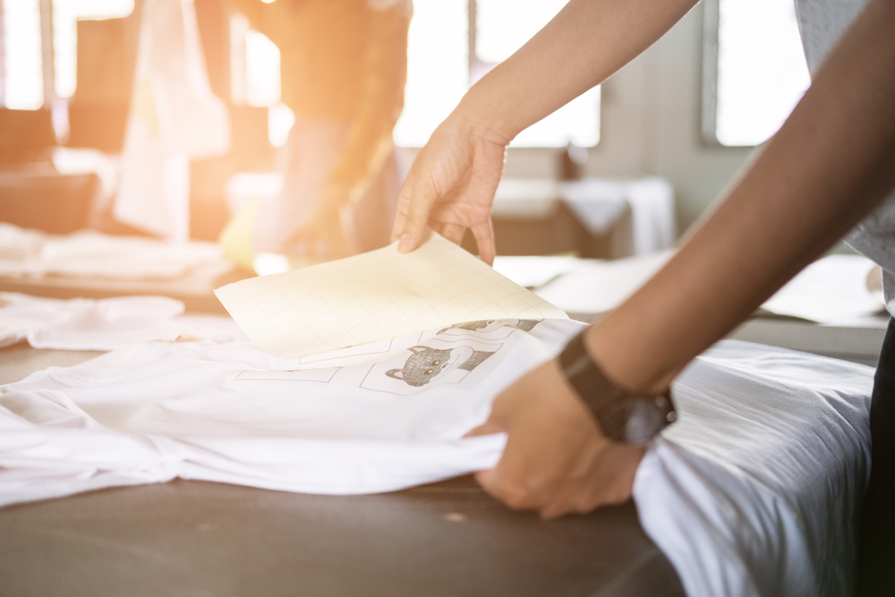 A man is putting stickers on a t-shirt
