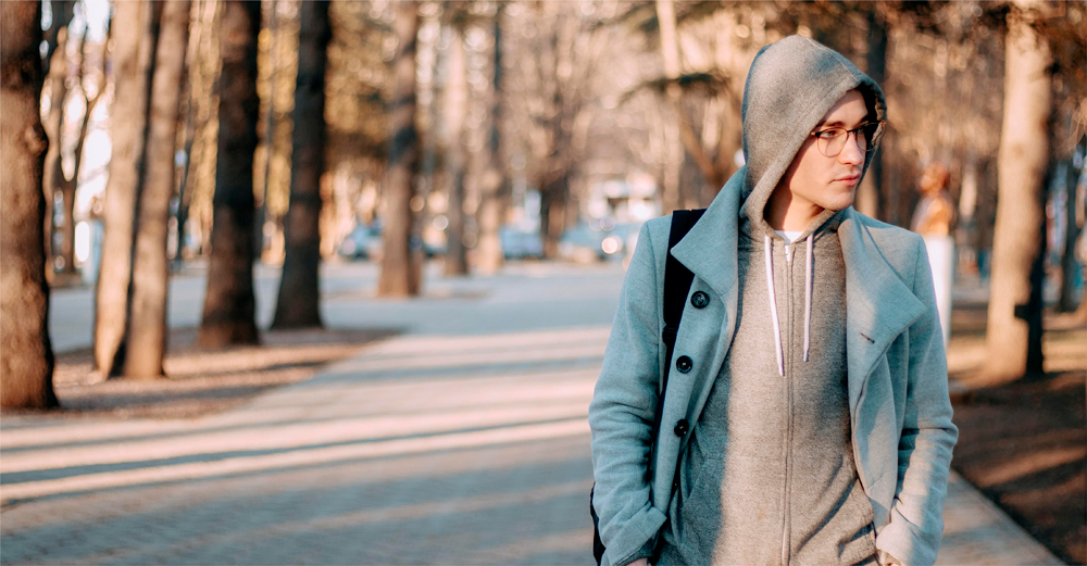 A man in a brown hoodie is on the side of the road