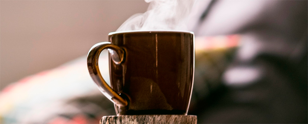 A brown mug full of coffee and steaming