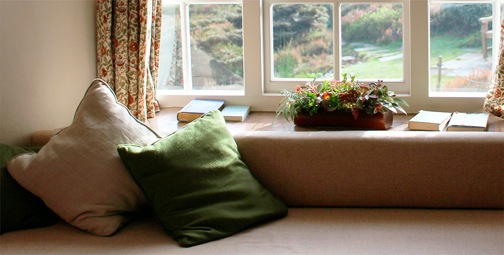 a green cushion is placed next to the bay window