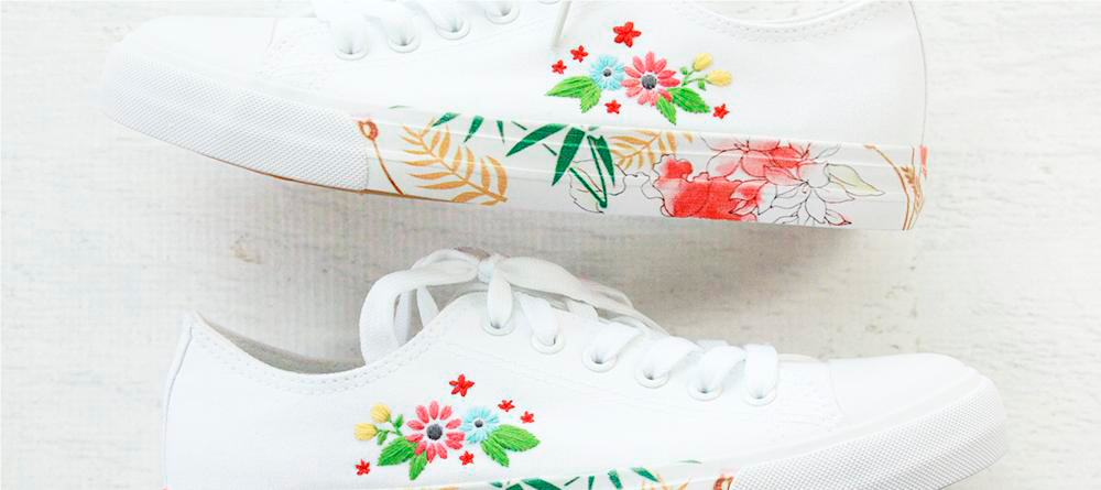 A pair of white canvas shoes with embroidery and flowers