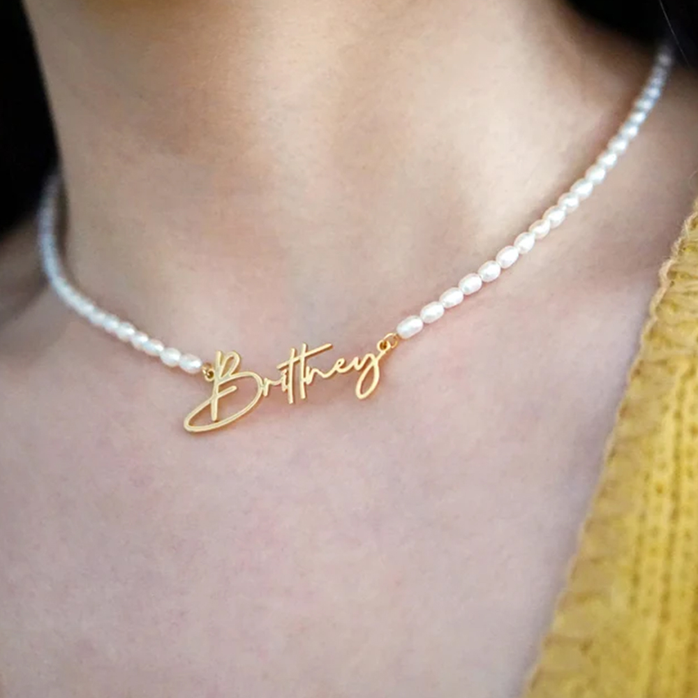 A female model wears a pearl necklace with an engraved lettering