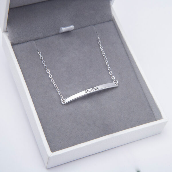 A silver text bracelet is placed in a jewelry box