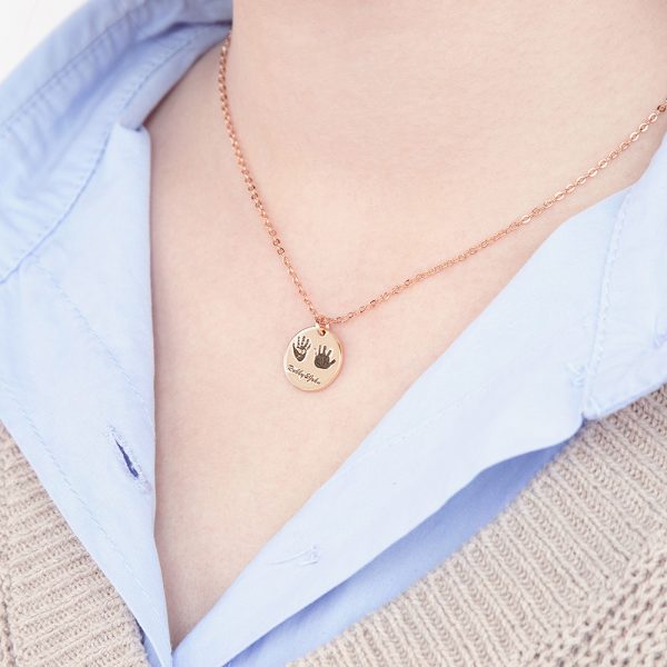 A female model wears a golden handprint necklace