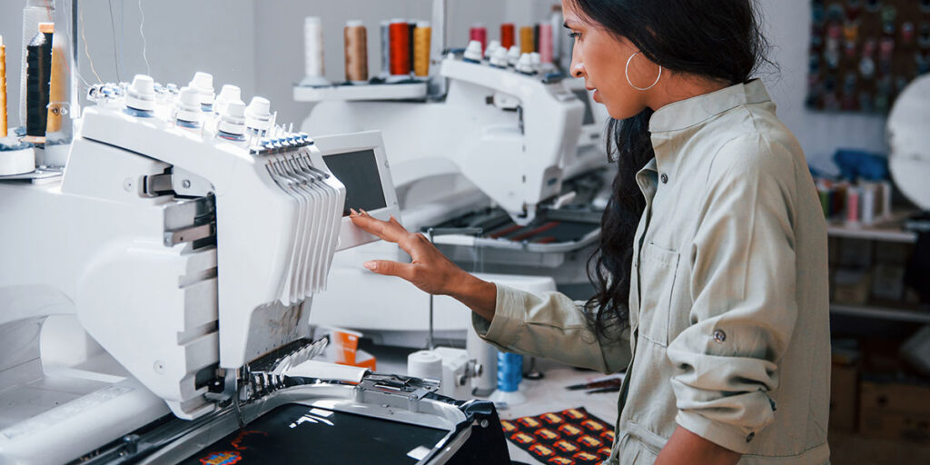 A woman is operating an embroidery machine