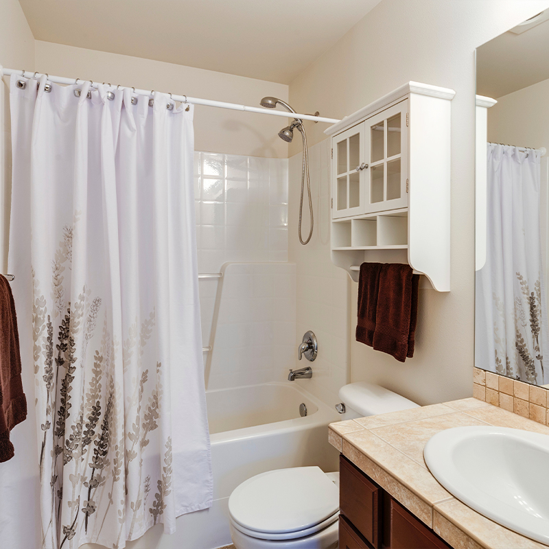 a floral shower curtain hangs in the bathroom