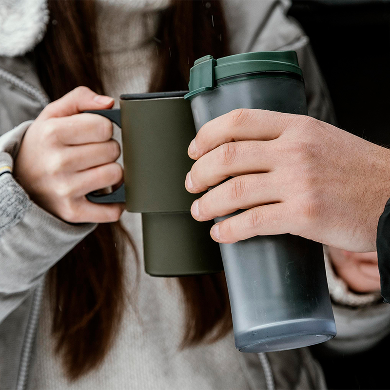 Two people are holding a thermos cup and doing a toast gesture