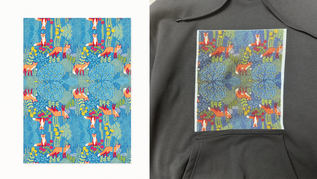A side-by-side image. The left shows a repeating illustrated pattern of orange foxes among dense blue leaves, green ferns, and yellow and red flowers. The right shows this same whimsical woodland pattern printed as a rectangular graphic on the chest of a dark gray hoodie.