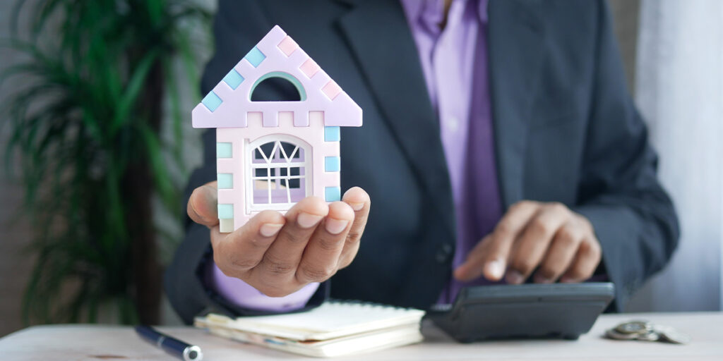 A model of a house sticks out of a male hand.