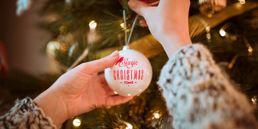 A person is decorating a Christmas tree using Christmas balls