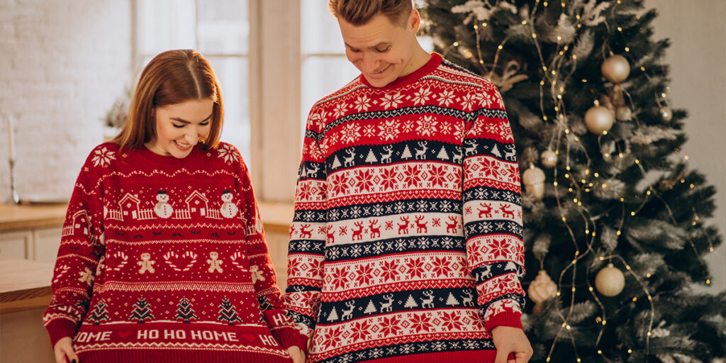 Two people looking at their Christmas sweaters