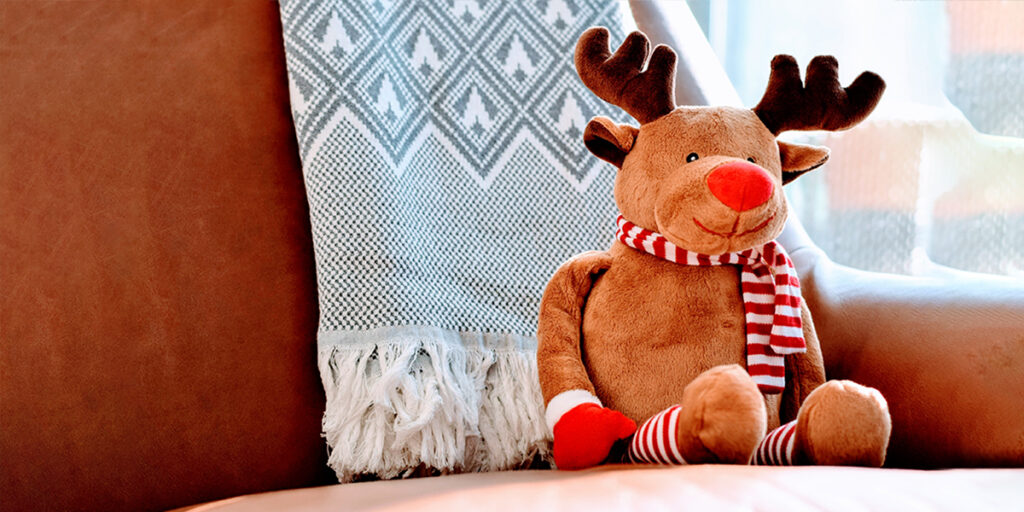 A stuffed Christmas elk is placed on the sofa