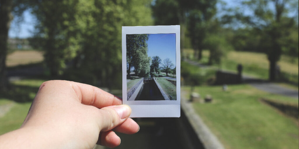 A person holding a beautiful landscape photo