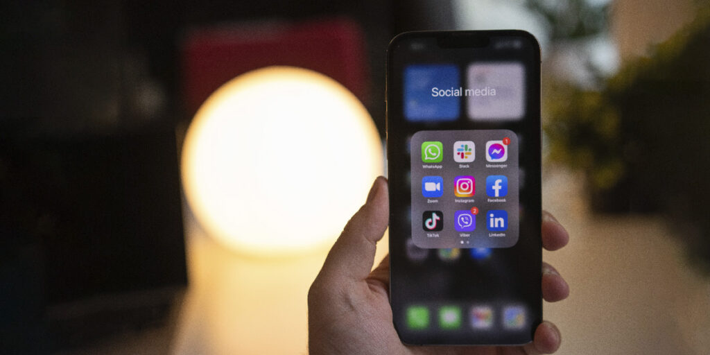 A person holds a smartphone with many social apps