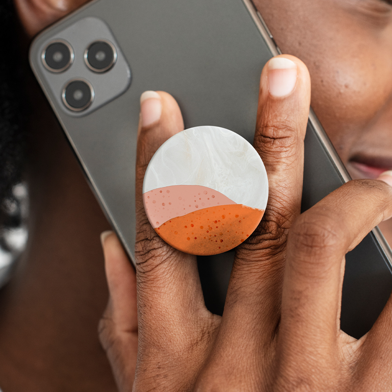 A woman talks on the phone using a cell phone with a phone grip.