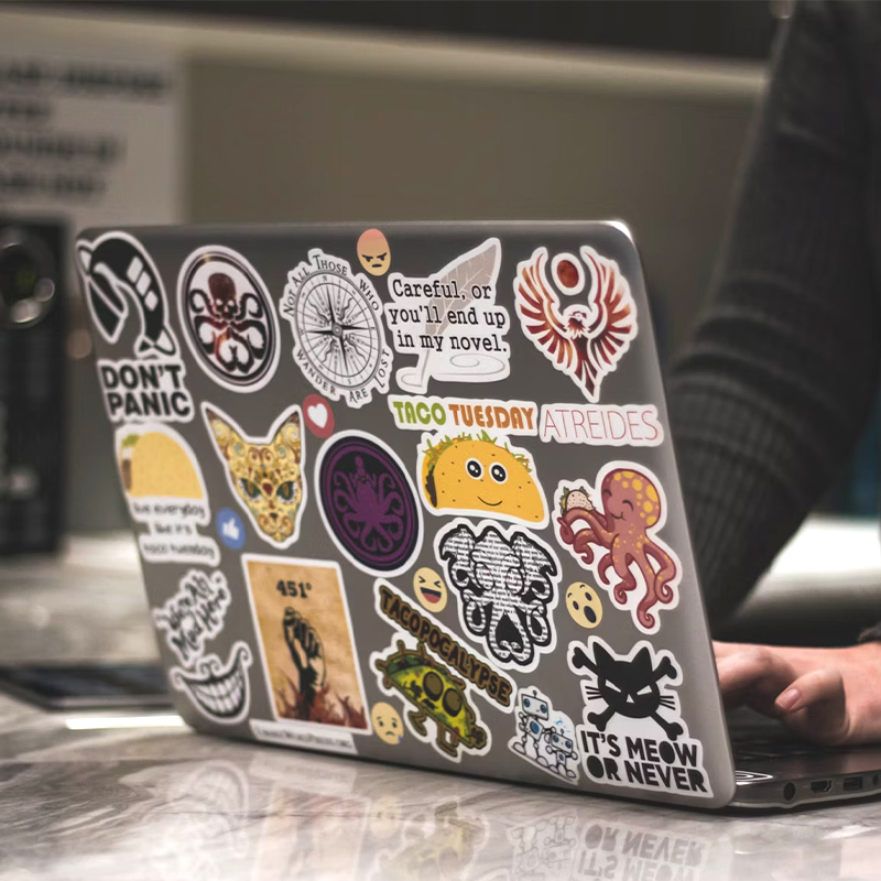 There are many cartoon stickers on the back of a macbook