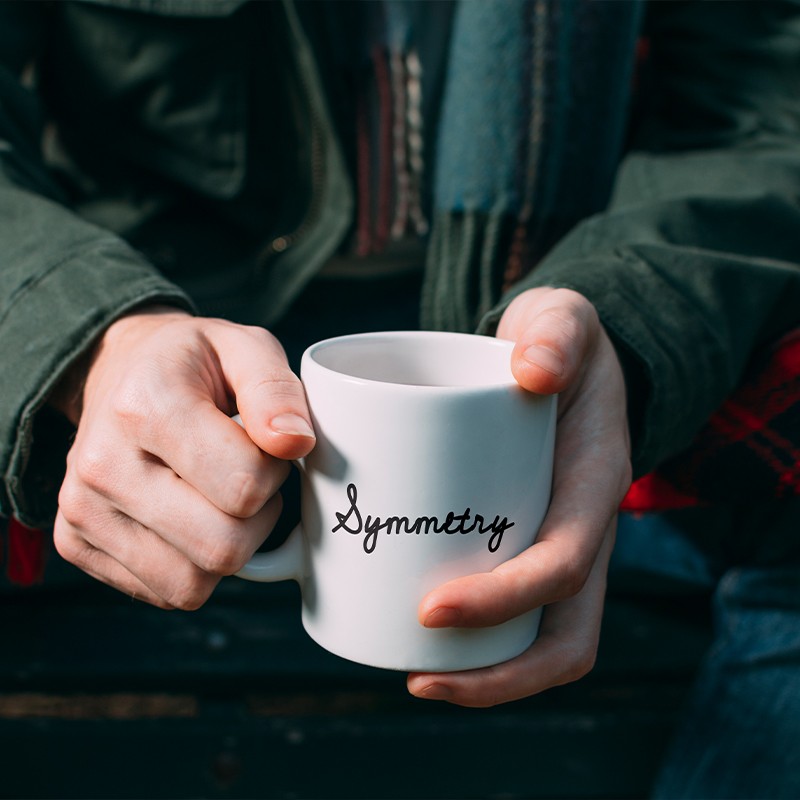 A person holding a white mug with a name on it