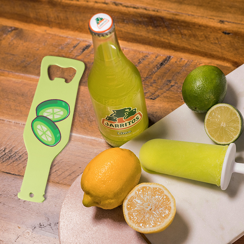 A green bottle opener lies next to a lemon and beer