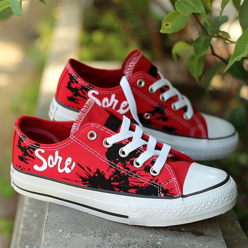 A pair of red low-top canvas shoes with personalized text