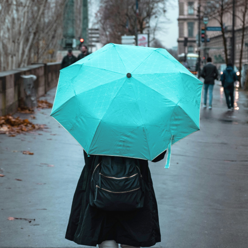 A person walking on the street holding a light blue umbrella