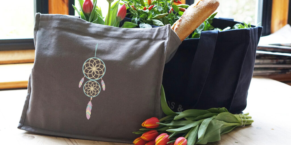 A black tote bag with a bohemian pattern is placed on a table