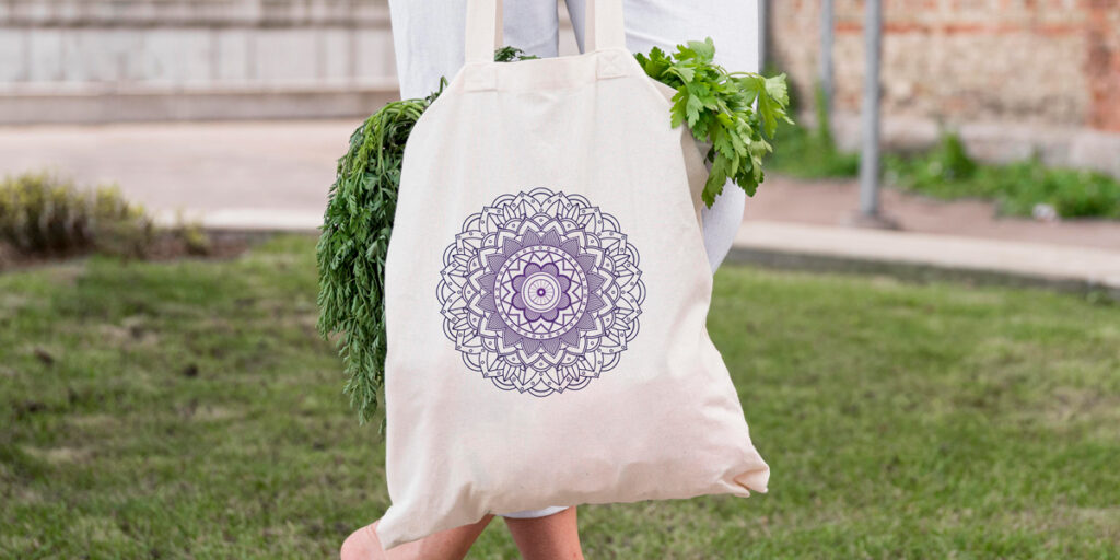 A woman holds a tote bag with mandala patterns