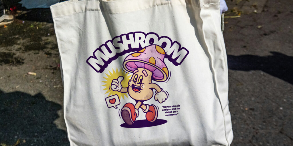 A woman holds a tote bag with a cartoon mushroom design