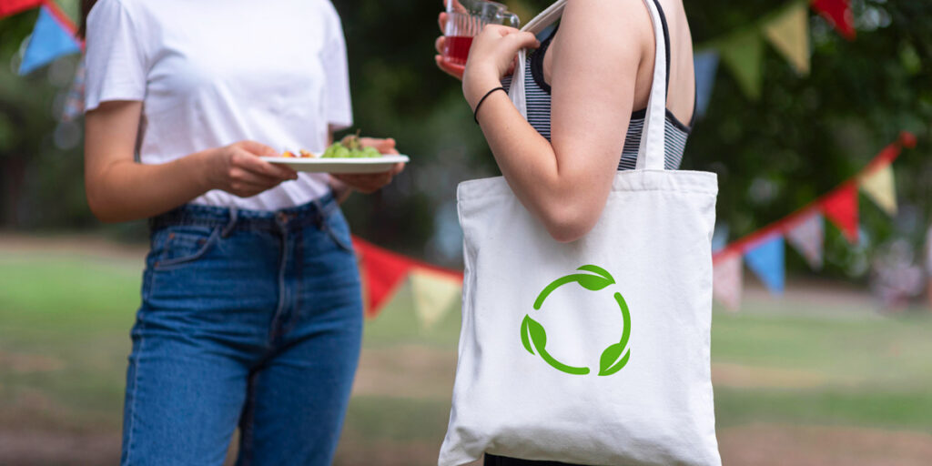 A woman carries a white tote bag with an eco-friendly design