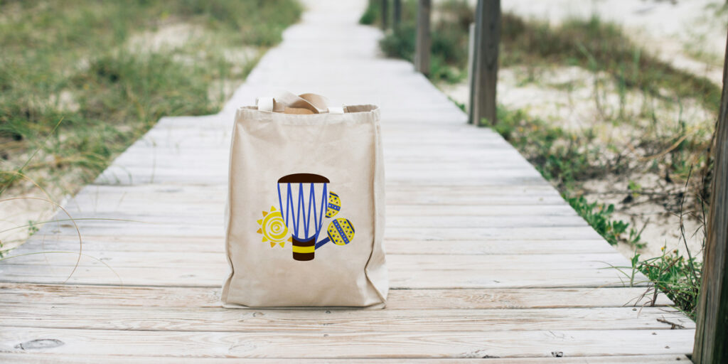 A tote bag with a Brazilian-style pattern is placed on the ground