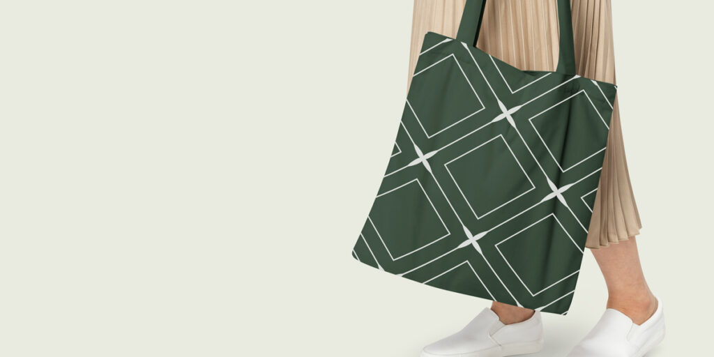 A woman carries a green tote bag with a geometric pattern