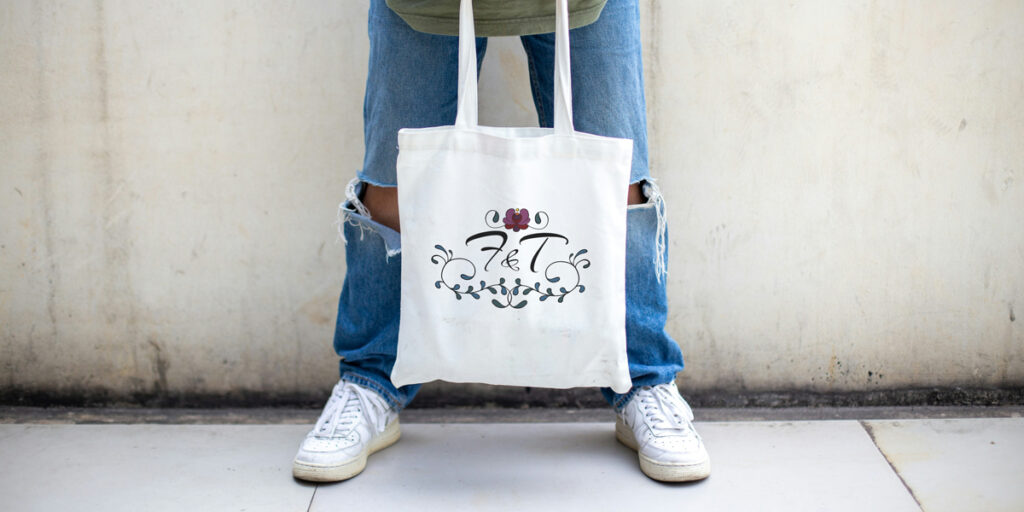 A man holds a monogrammed tote bag