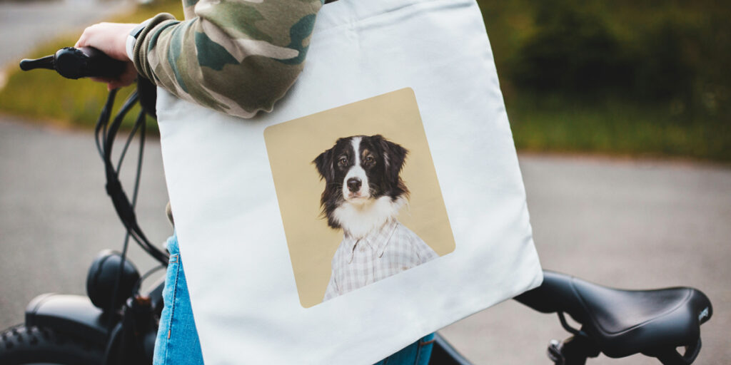 A woman holds a tote bag with a portrait of a pet dog