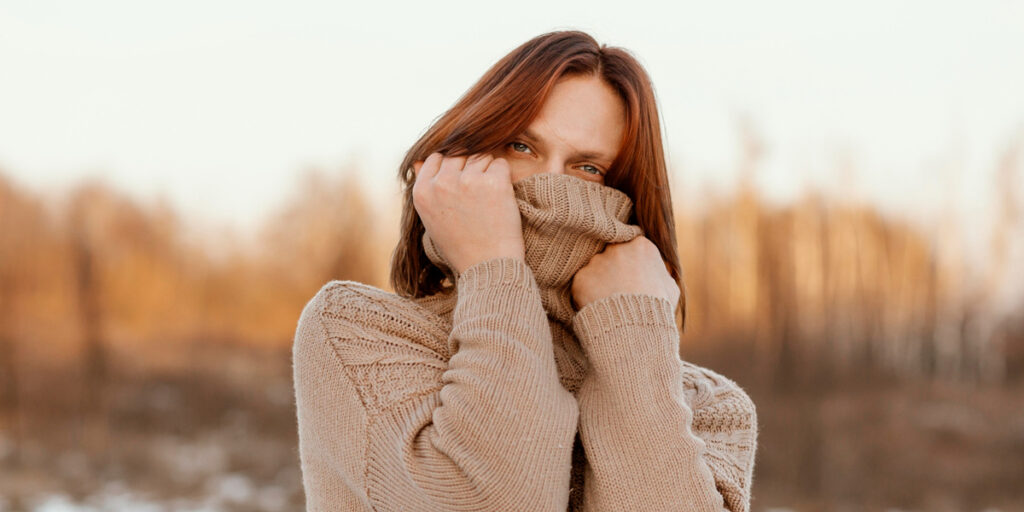 A woman wearing a beige turtleneck sweater